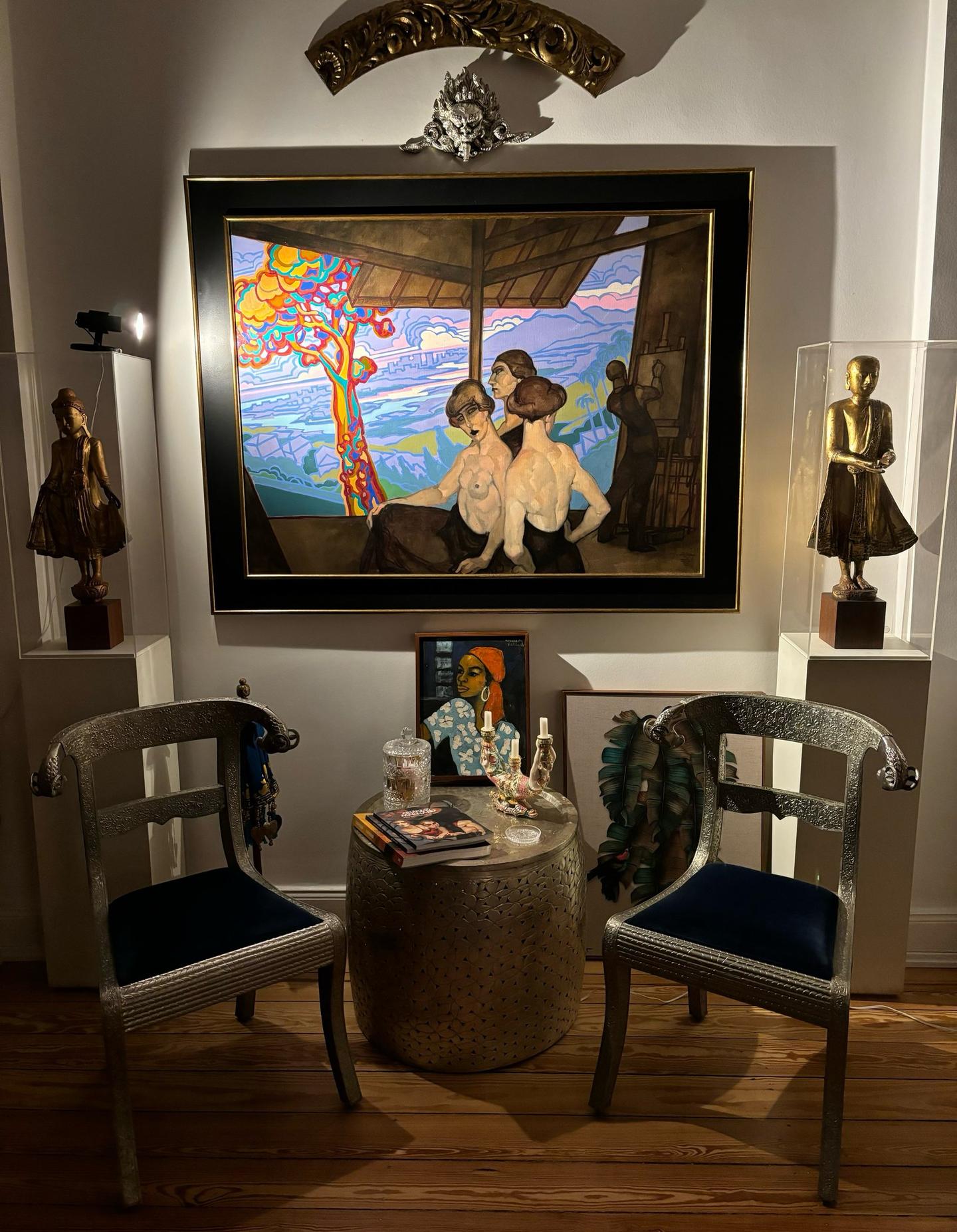 A gold-framed Juarez Machado painting displayed between antique gilt figures in vitrines at Art House Winterhude